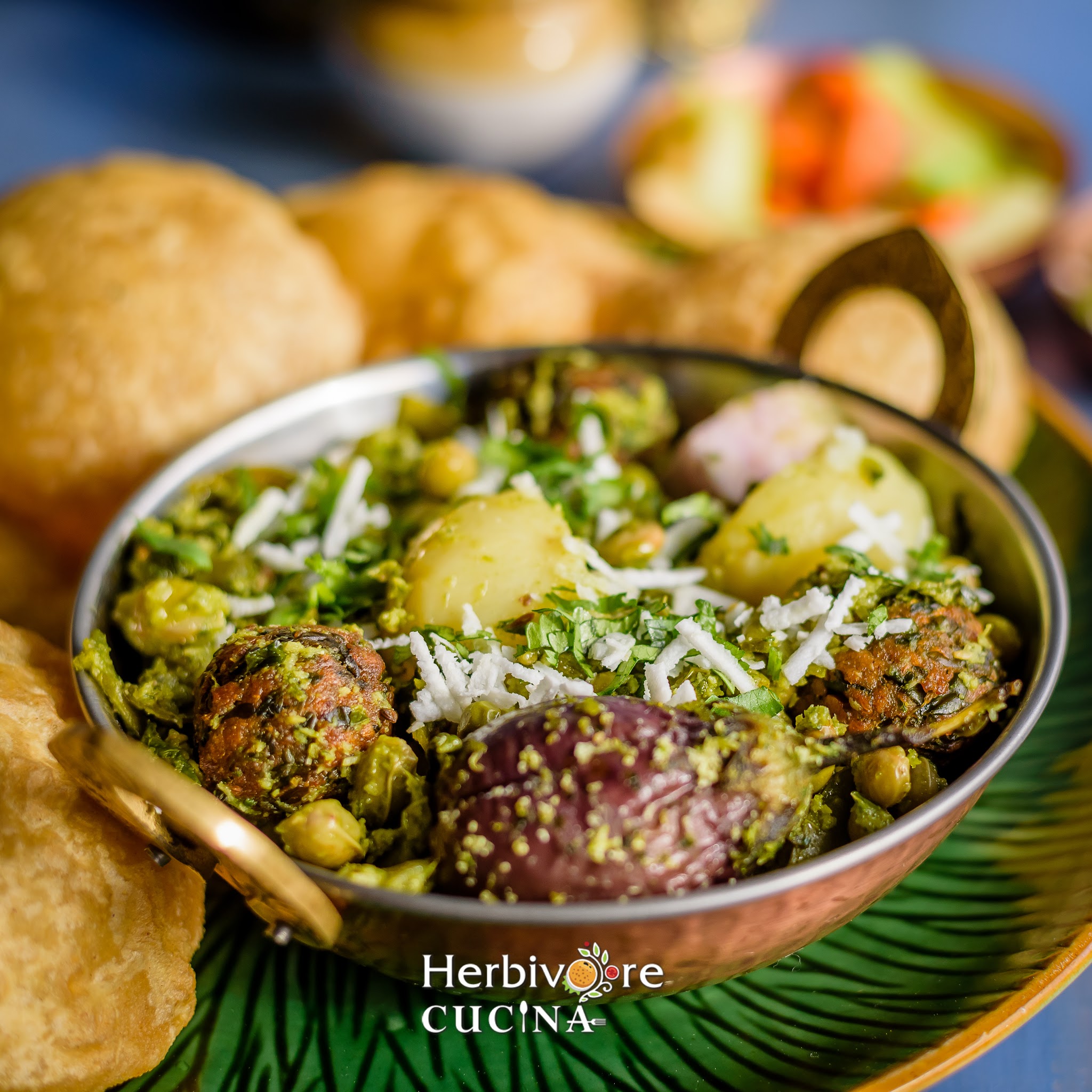 A copper bowl filled with undhiyu and served with puris on the side in a green plate. 