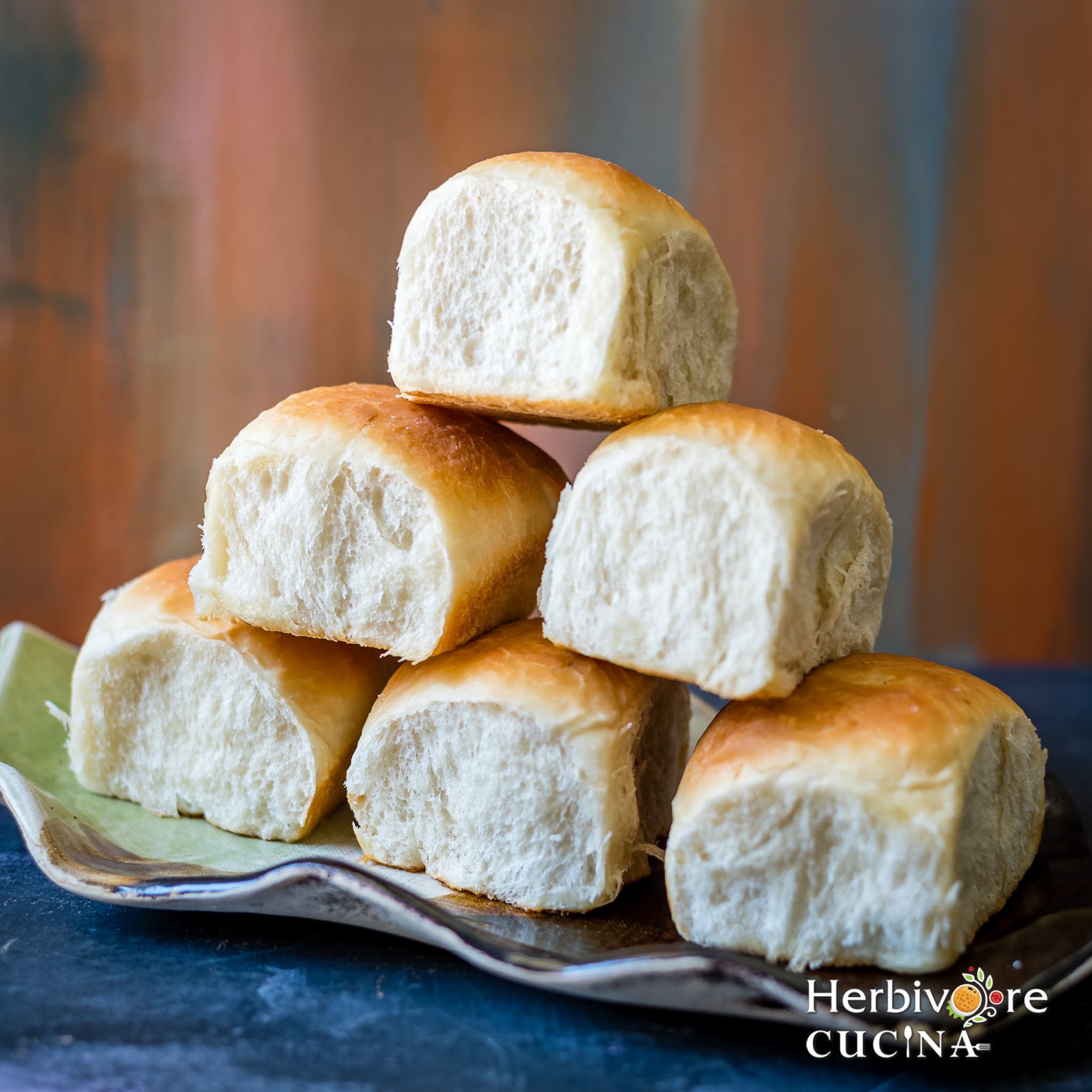 Six slider buns stacked in a tray and placed on a dark surface. 