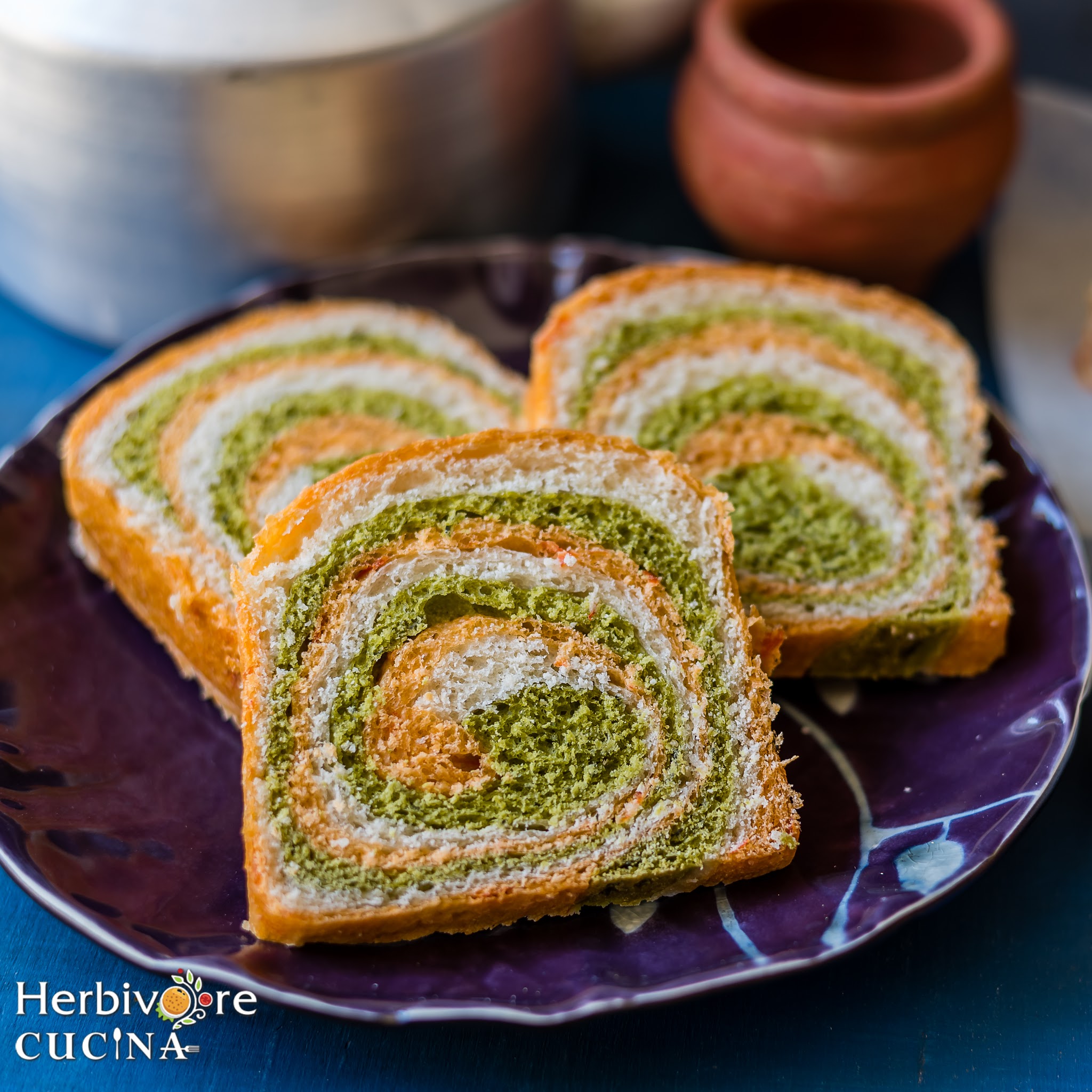 A violet plate with three slices of tricolor swirl bread. 