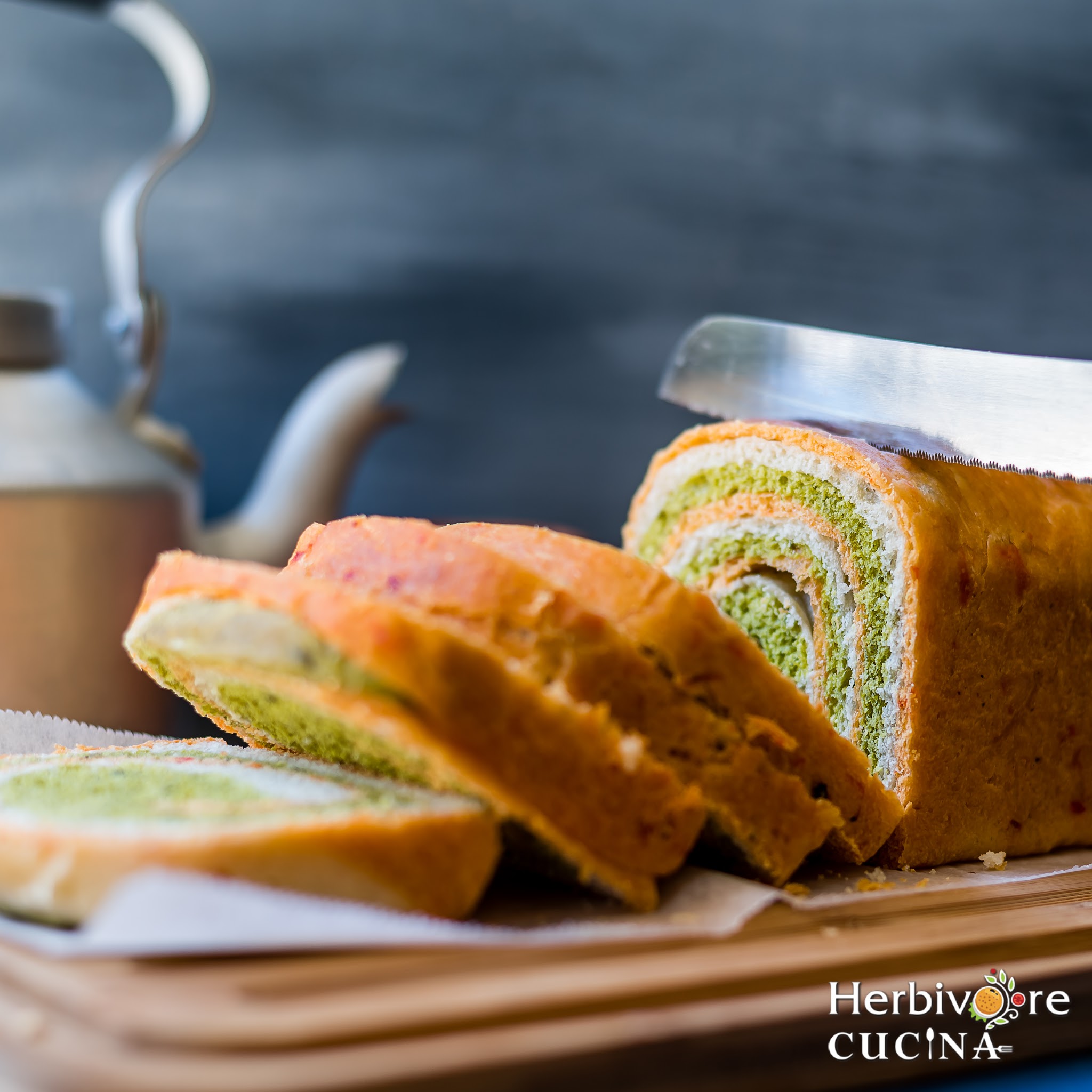 Slicing a loaf of tricolor swirl bread with a knife on a wooden block. 