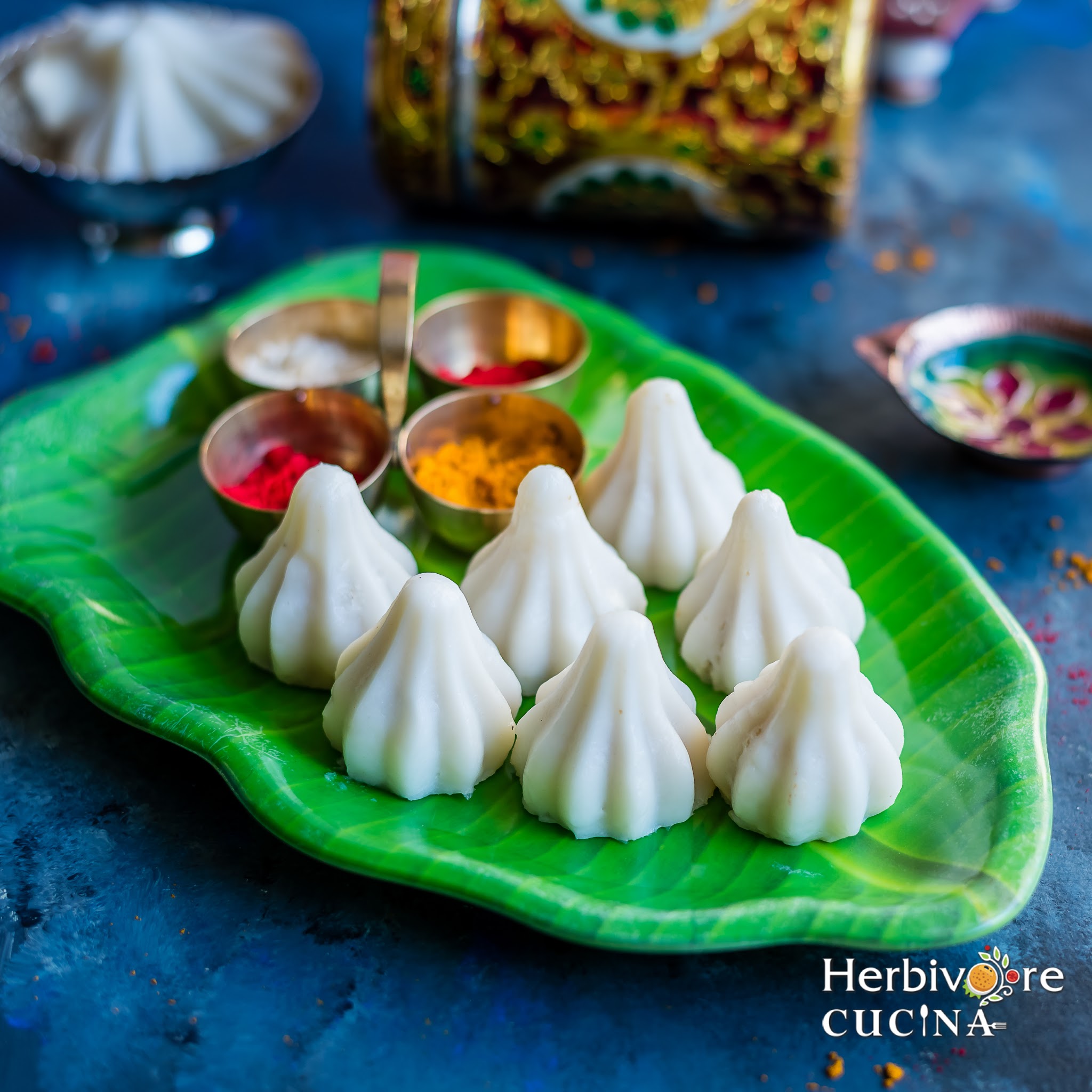 A leaf shaped platter with steamed rice flour modaks with other pooja elements. 