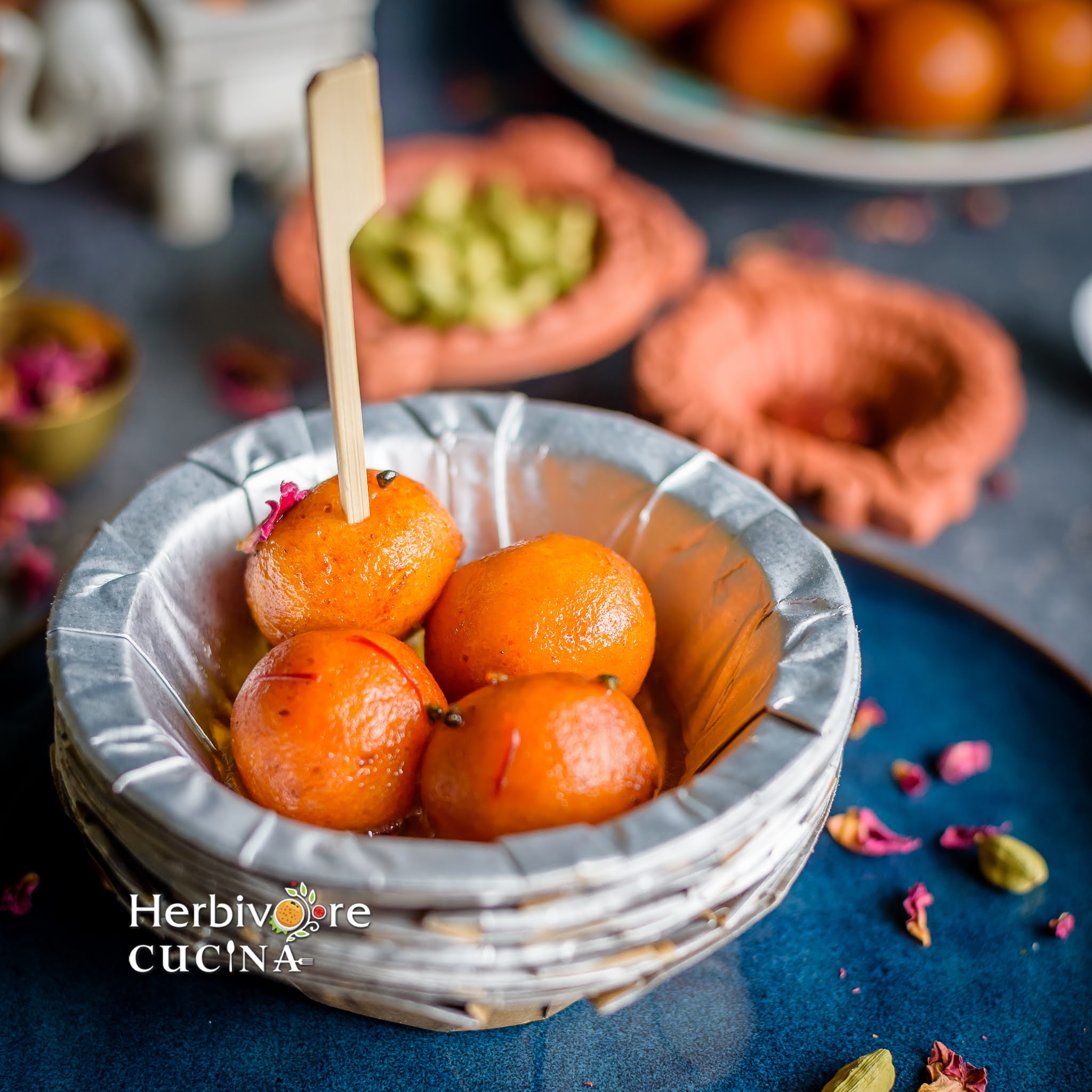 Bowls with four ricotta cheese gulab jamins with diyas on the side.