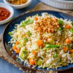 A blue plate with burnt garlic fried rice with a fork on the side.