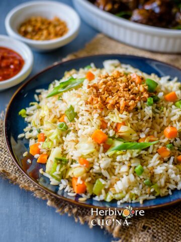A blue plate with burnt garlic fried rice with a fork on the side.