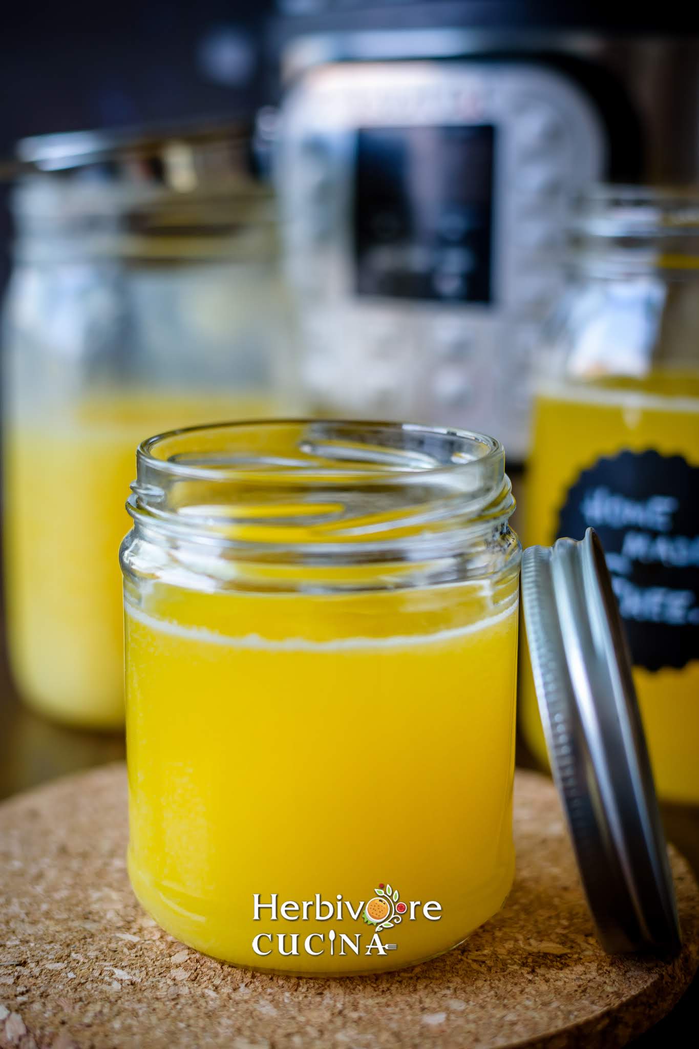 Cooled ghee in a glass container with the instant pit on the side and more ghee bottles placed beside it. 