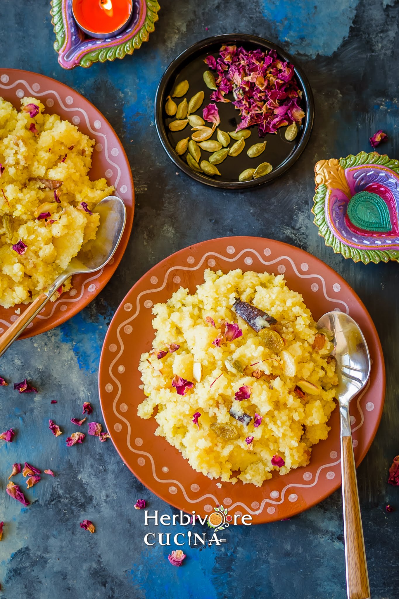 A brown plate with rava sheera in it and topped with saffron and dried rose petals with more ingredients on the side.