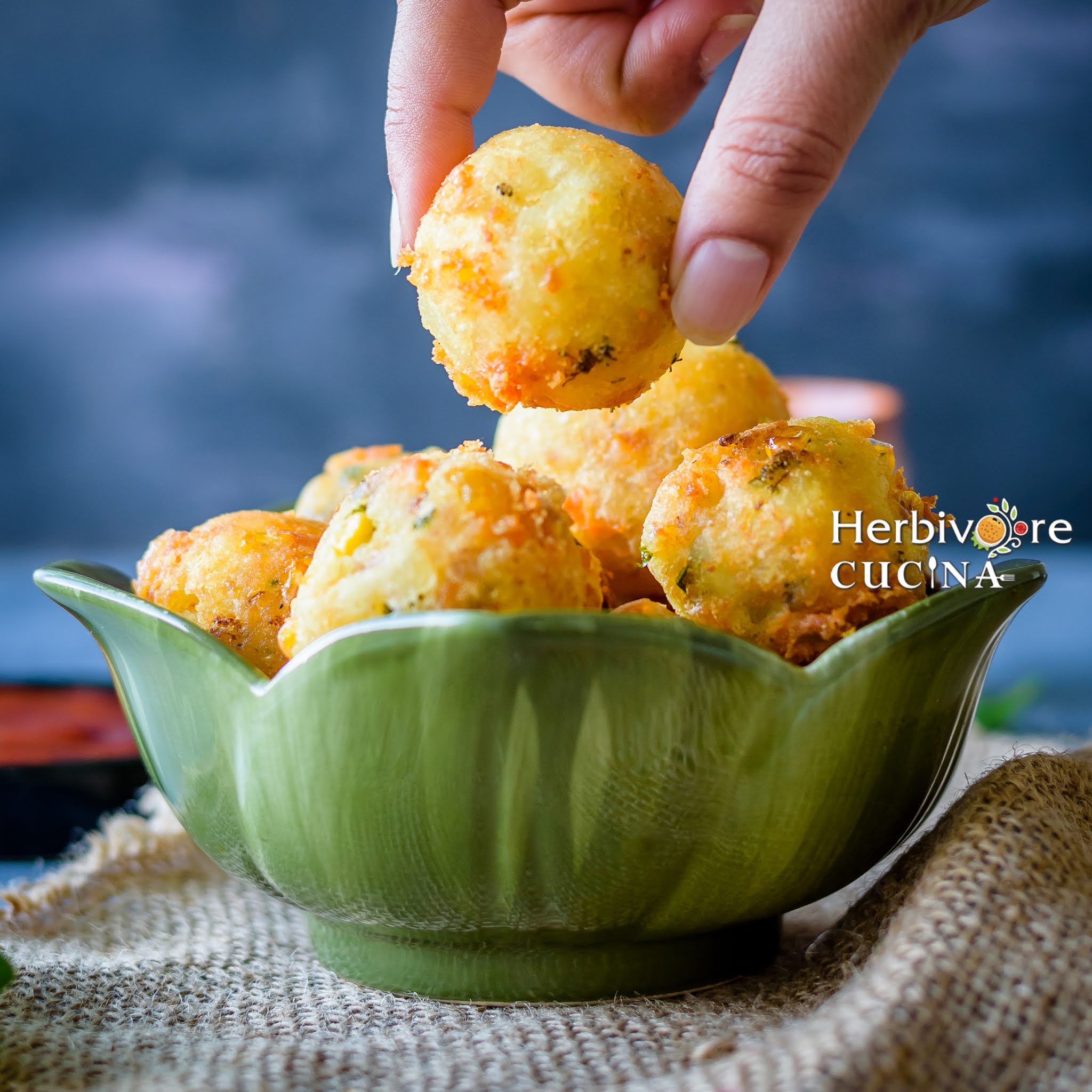 Vegetable Cheese balls held in hand on a bowl full of these balls.