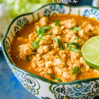 A bowl of crumbled tofu sofritas in a smoky chipotle sauce topped with fresh cilantro and a lime wedge, served with rice.