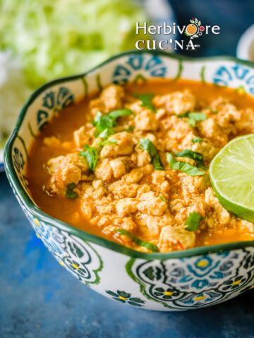 A bowl of crumbled tofu sofritas in a smoky chipotle sauce topped with fresh cilantro and a lime wedge, served with rice.