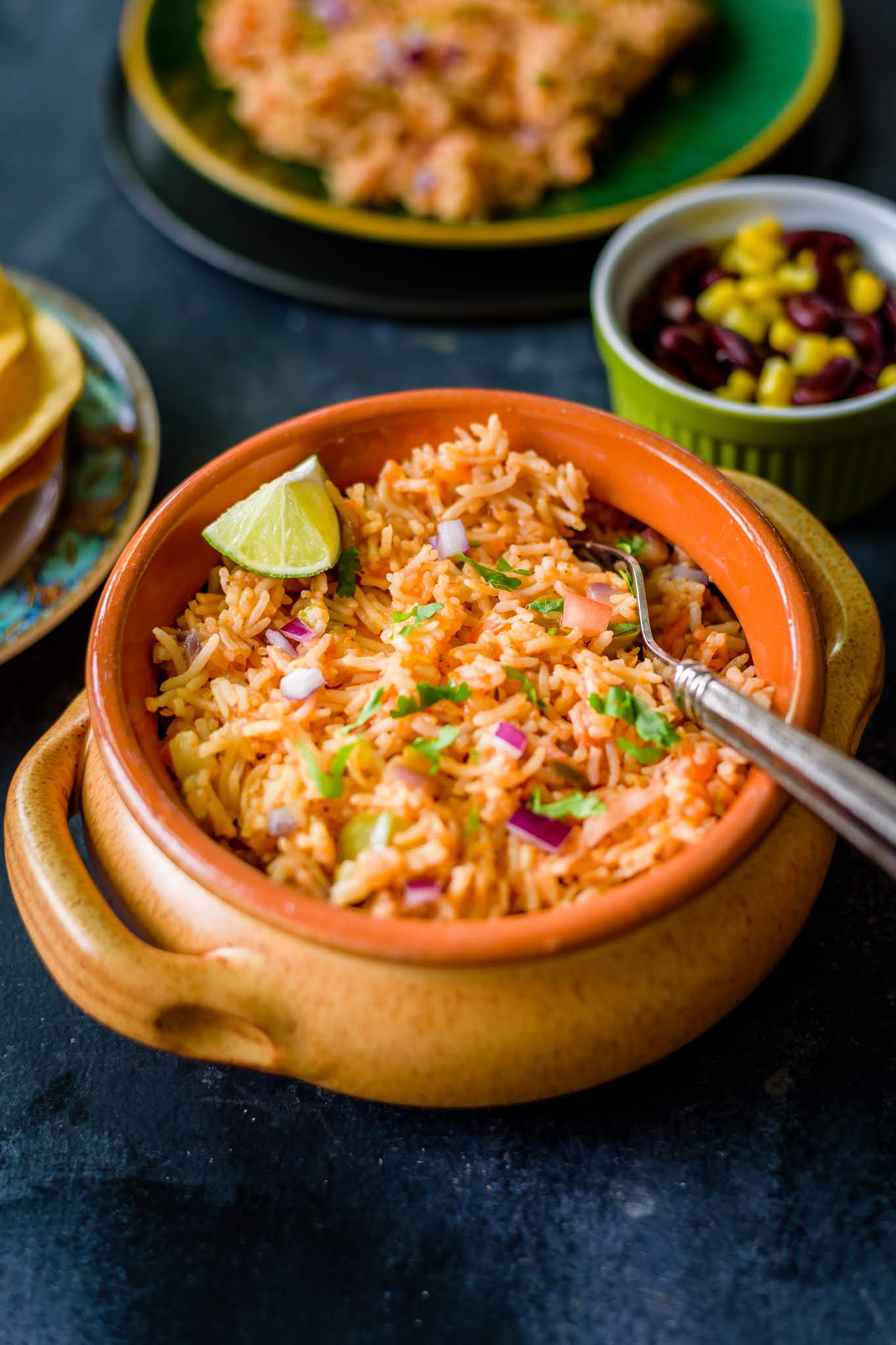 Side view of yellow bowl filled with Instant Pot Vegan Mexican Rice with a slice of lemon on the side. 