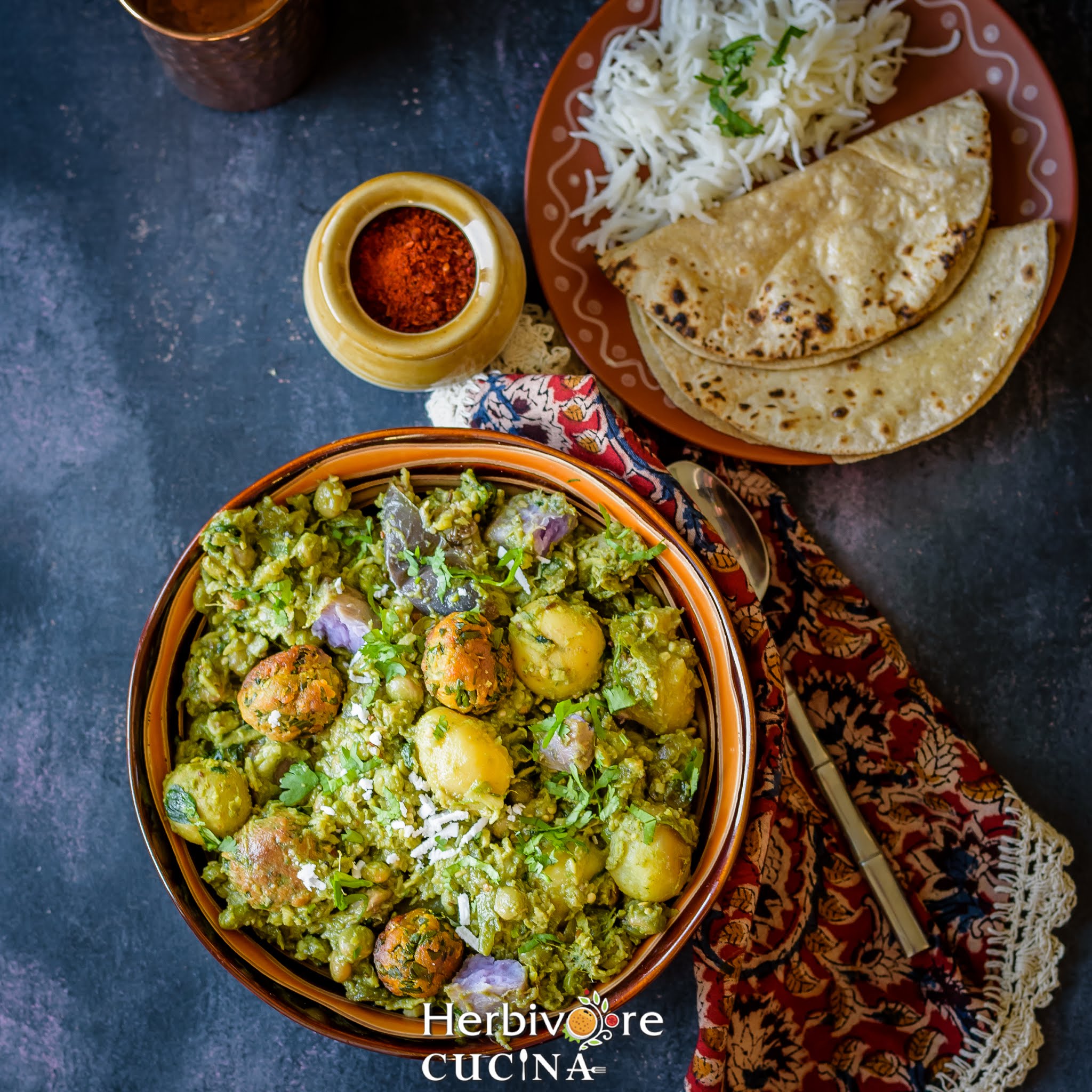 Instant Pot Undhiyu in a brown bowl with chutney and roti on the side on a black background.