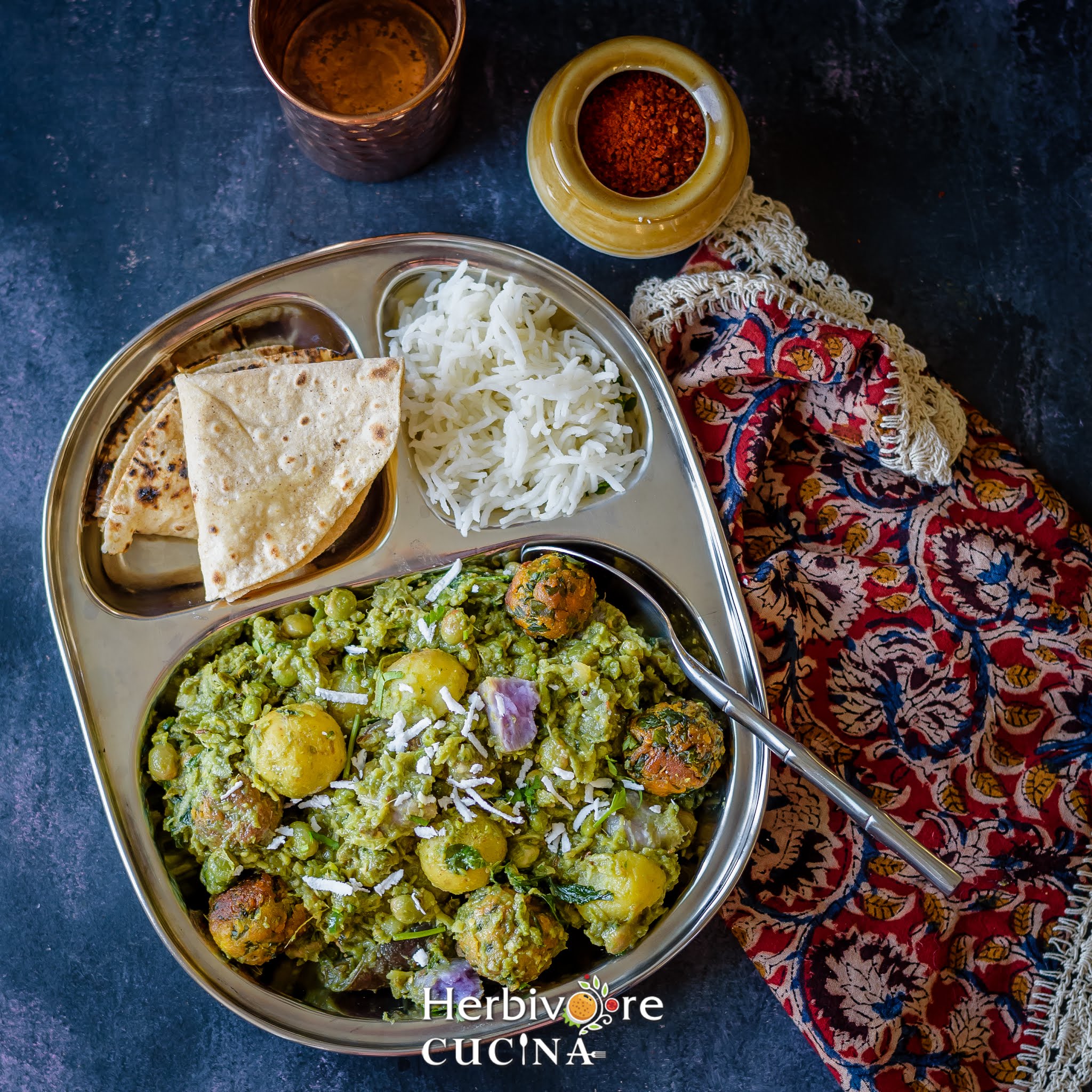 Serving undhiyu in a steel plate with roti and rice; with some chutney on the side. 