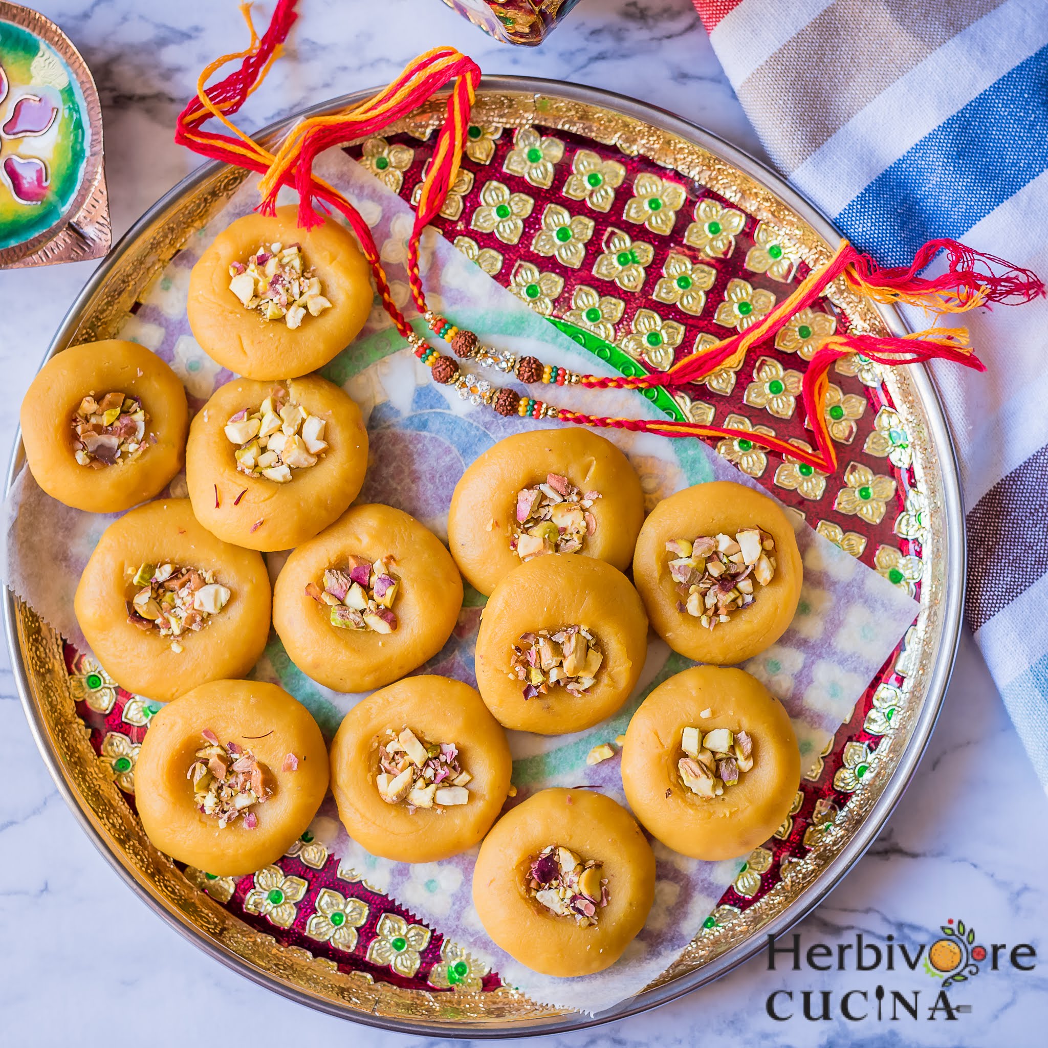 A platter with microwave kesar peda and rakhis beside it.