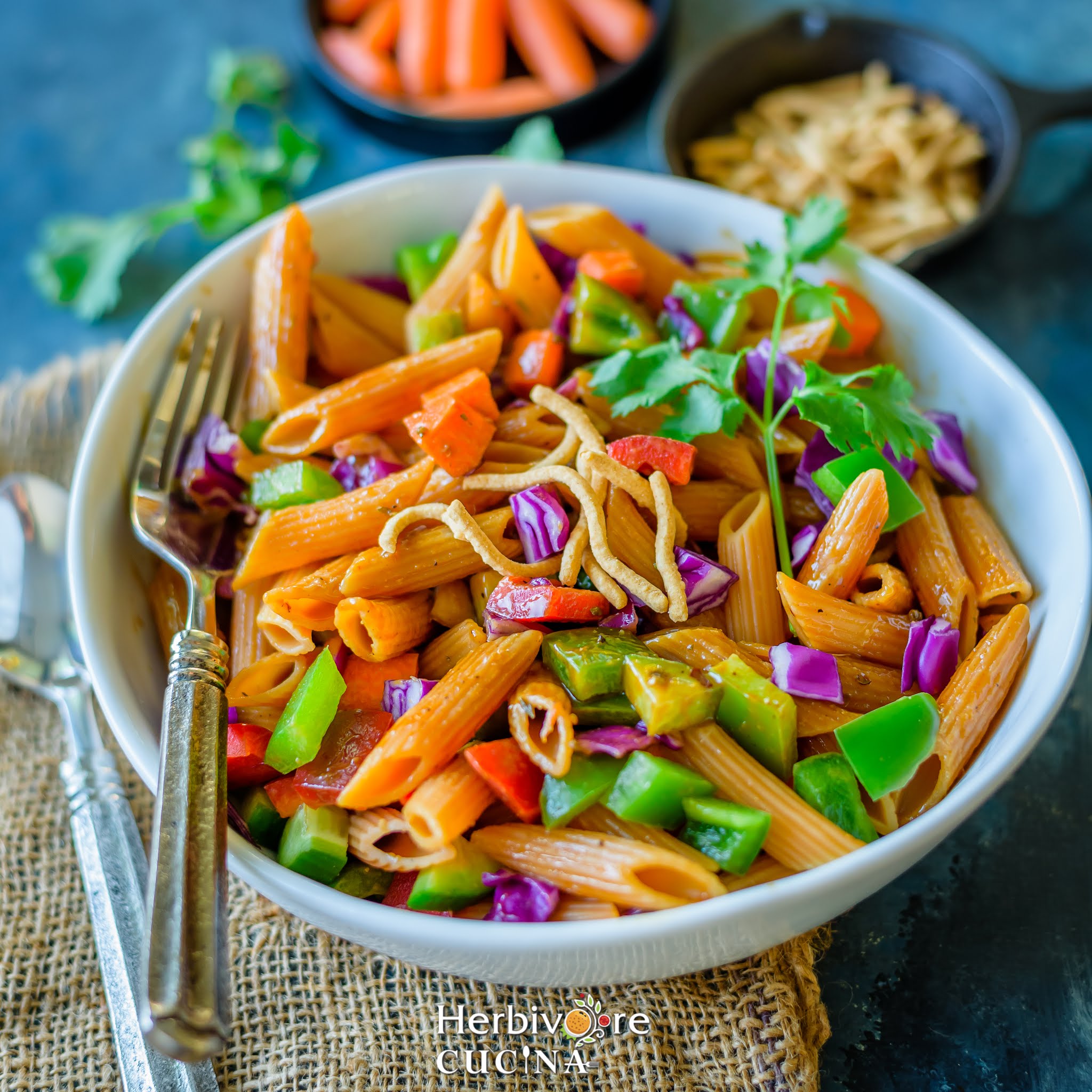 Vegan Thai Salad served in a white bowl topped with fried noodles with some chopped peanuts on the side.