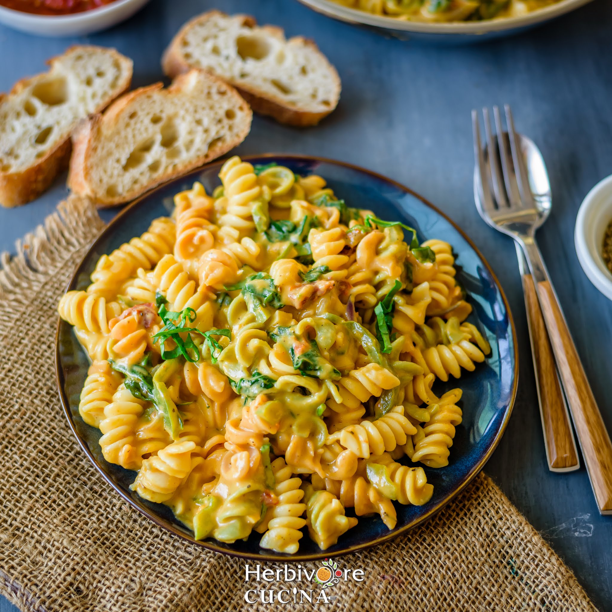 A blue plate with one pot pumpkin sauce pasta served with baguette slices on the side.