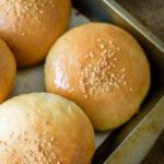 A platter with burger buns topped with sesame seeds.