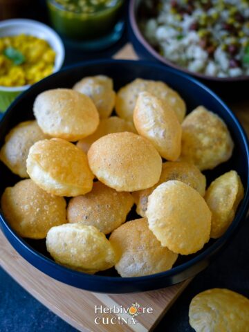 Blue platter with fried puris for pani puri and other chaats with more chaat ingredients around it.