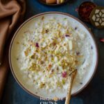 Creamy Instant Pot Kheer topped with dried rose petals and slivered almonds and pistachios in a bowl.