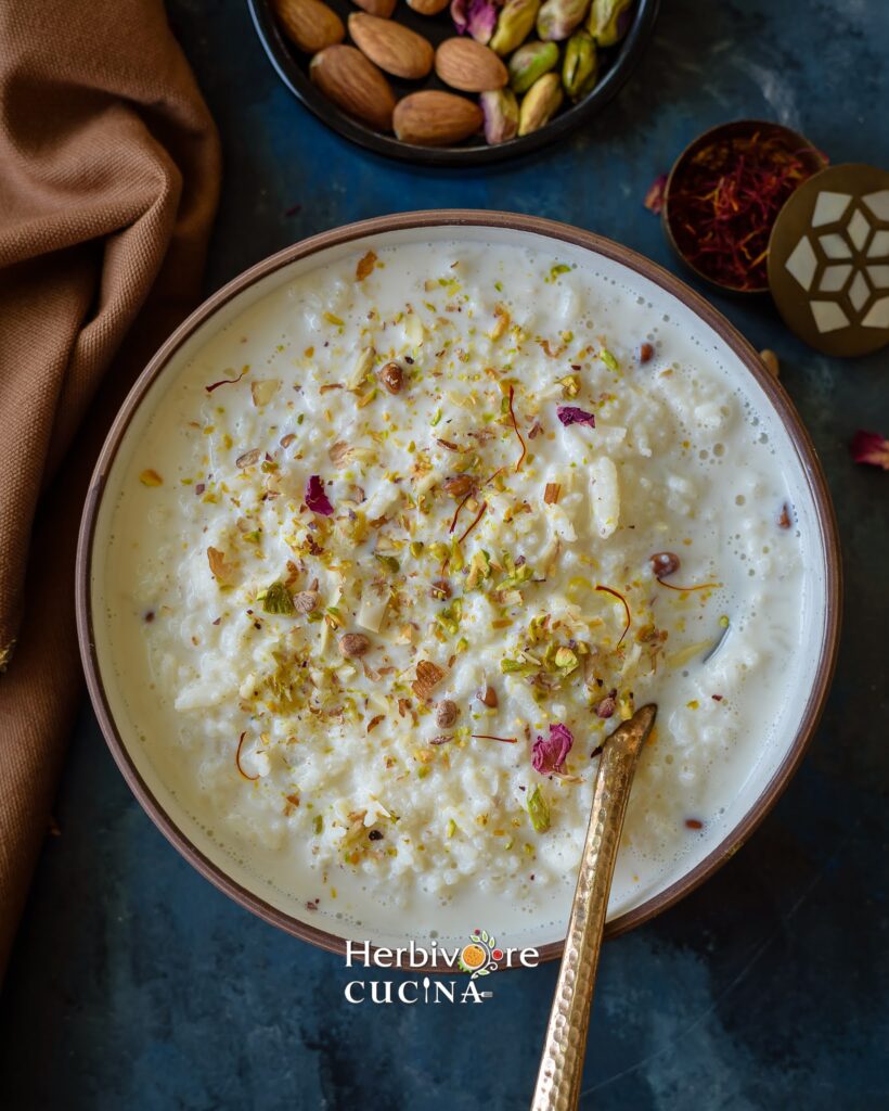 Creamy Instant Pot Kheer topped with dried rose petals and slivered almonds and pistachios in a bowl.