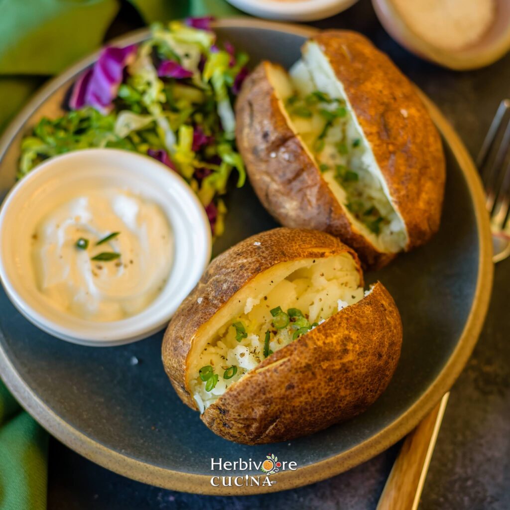 A close-up of two halved air fryer baked potatoes with a fluffy, steaming white interior and a golden-brown, crispy salted skin.