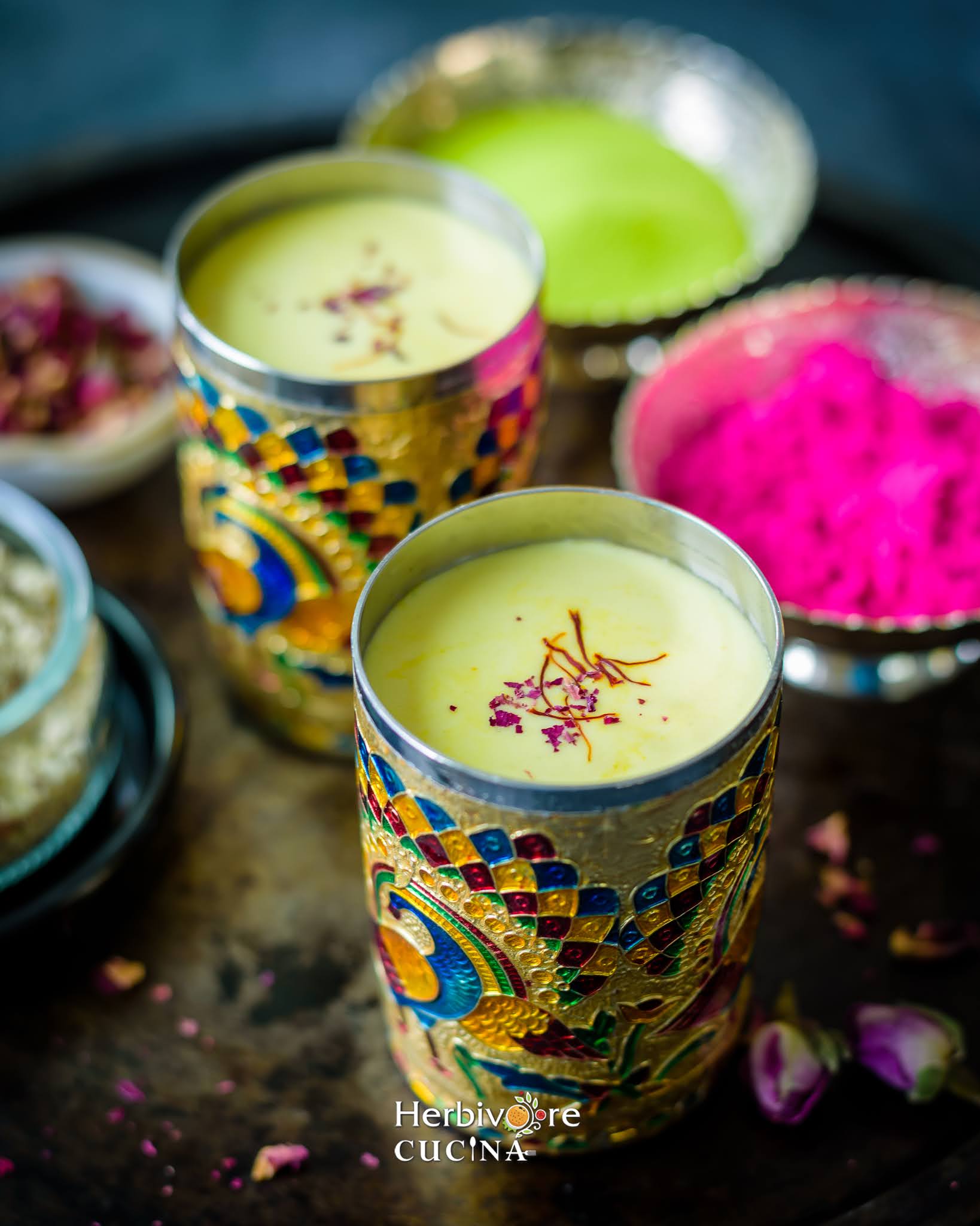 Thandai or Sardai; a milk based spiced and nutty drink served in fancy glasses with Holi colors in the background. 
