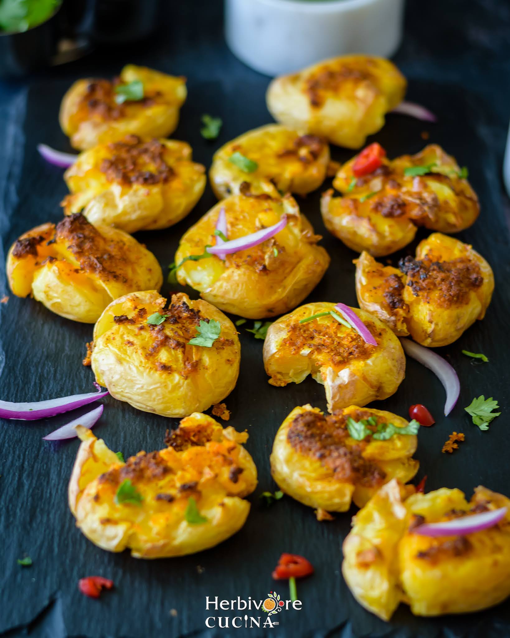 Air Fried Masala Smashed Potatoes topped with red onions, chili and cilantro.