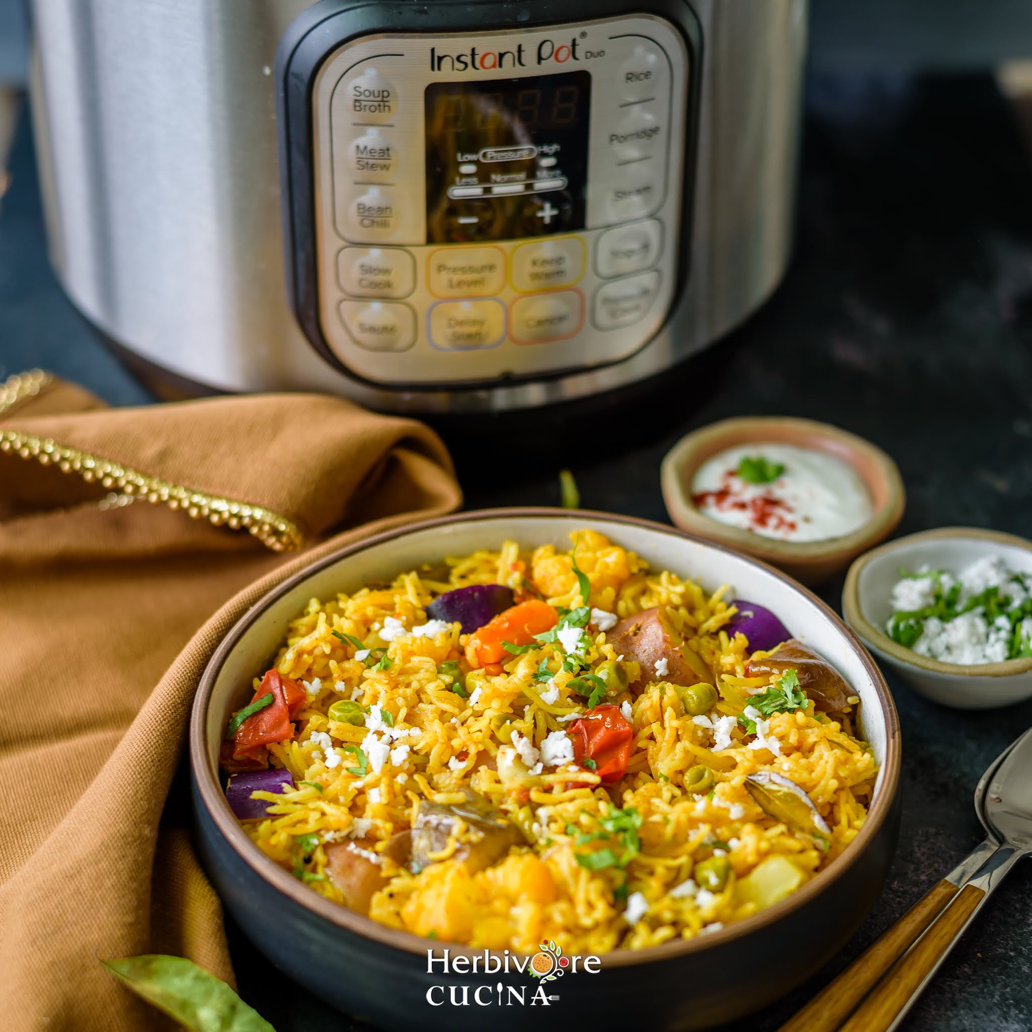 A bowl of instant pot masale bhaat with an instant pot right behind it and yogurt served by the side. 