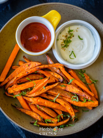 A plate full of air fried sweet potato fries with dips and ketchup