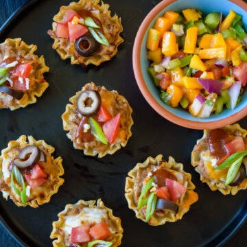 Plate with air fried mexican pizza cups with a bowl of mango salsa beside it.