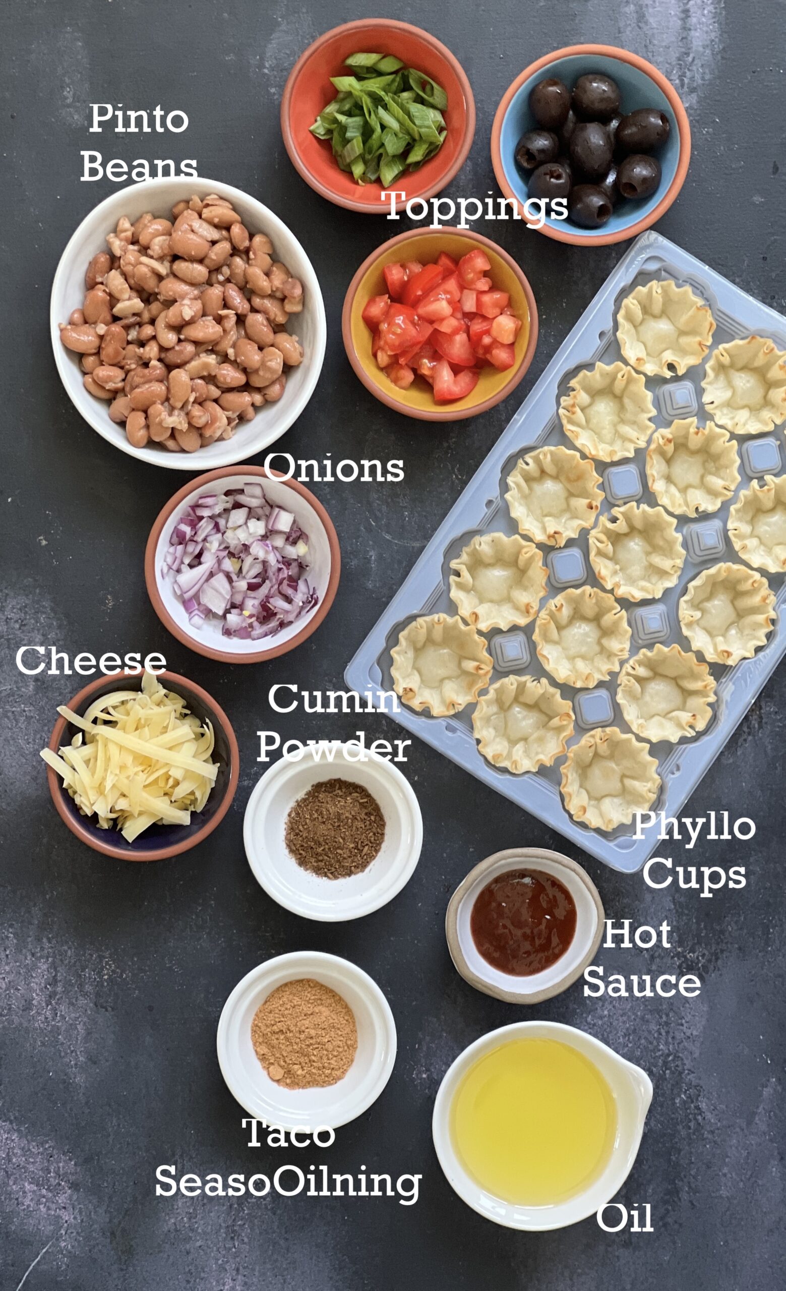 Ingredients to make Mexican Pizza Cups in small bowls on a dark surface. 