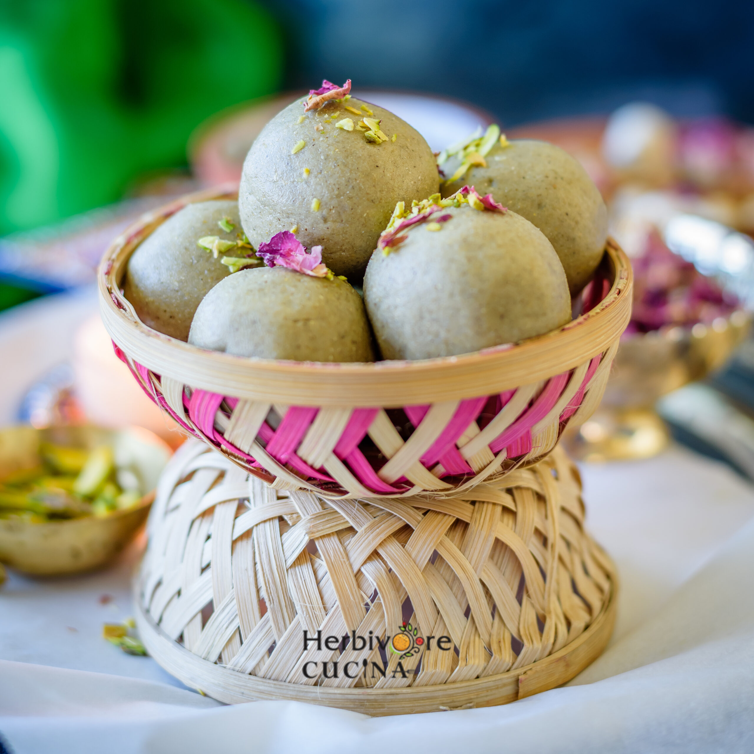 A basket filled with Bajri jaggery ladoos; kuler ladoos topped with pistachios and rose petals. 