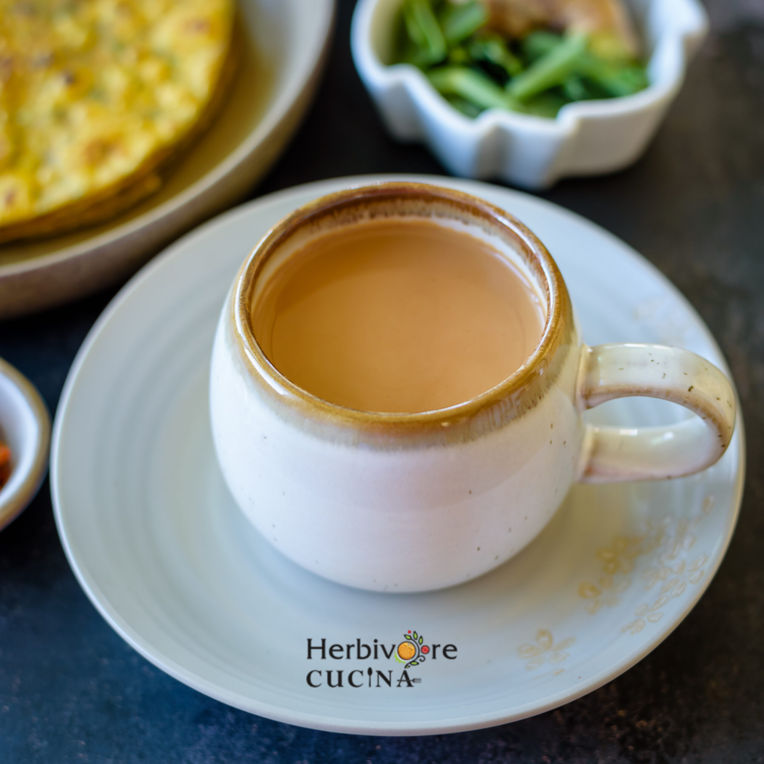 Masala chai in a white cup with a white saucer; with thepla and chai masala on the side. 
