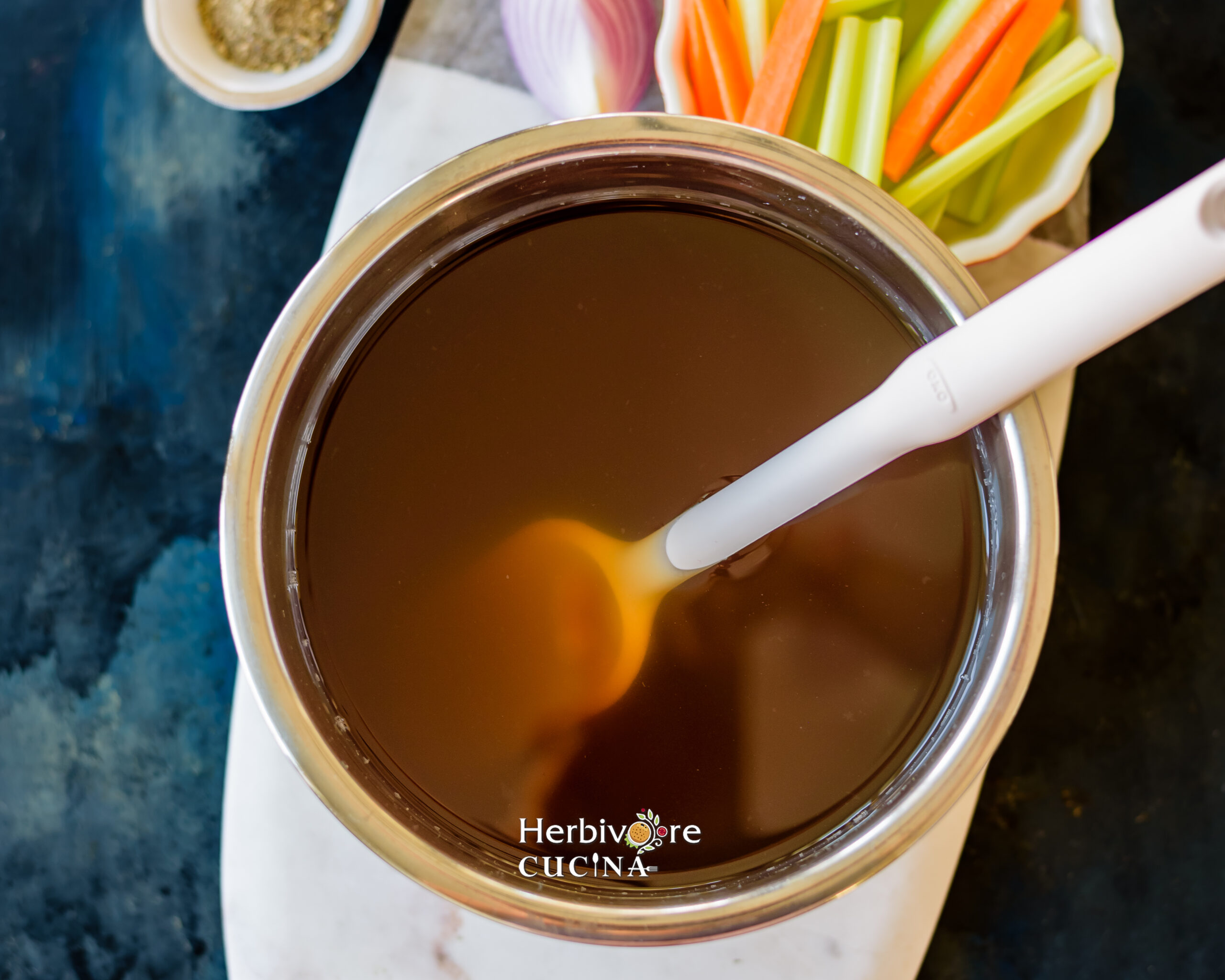Vegetable Stock in Instant Pot with a spatula on he side and chopped vegetables on the side. 