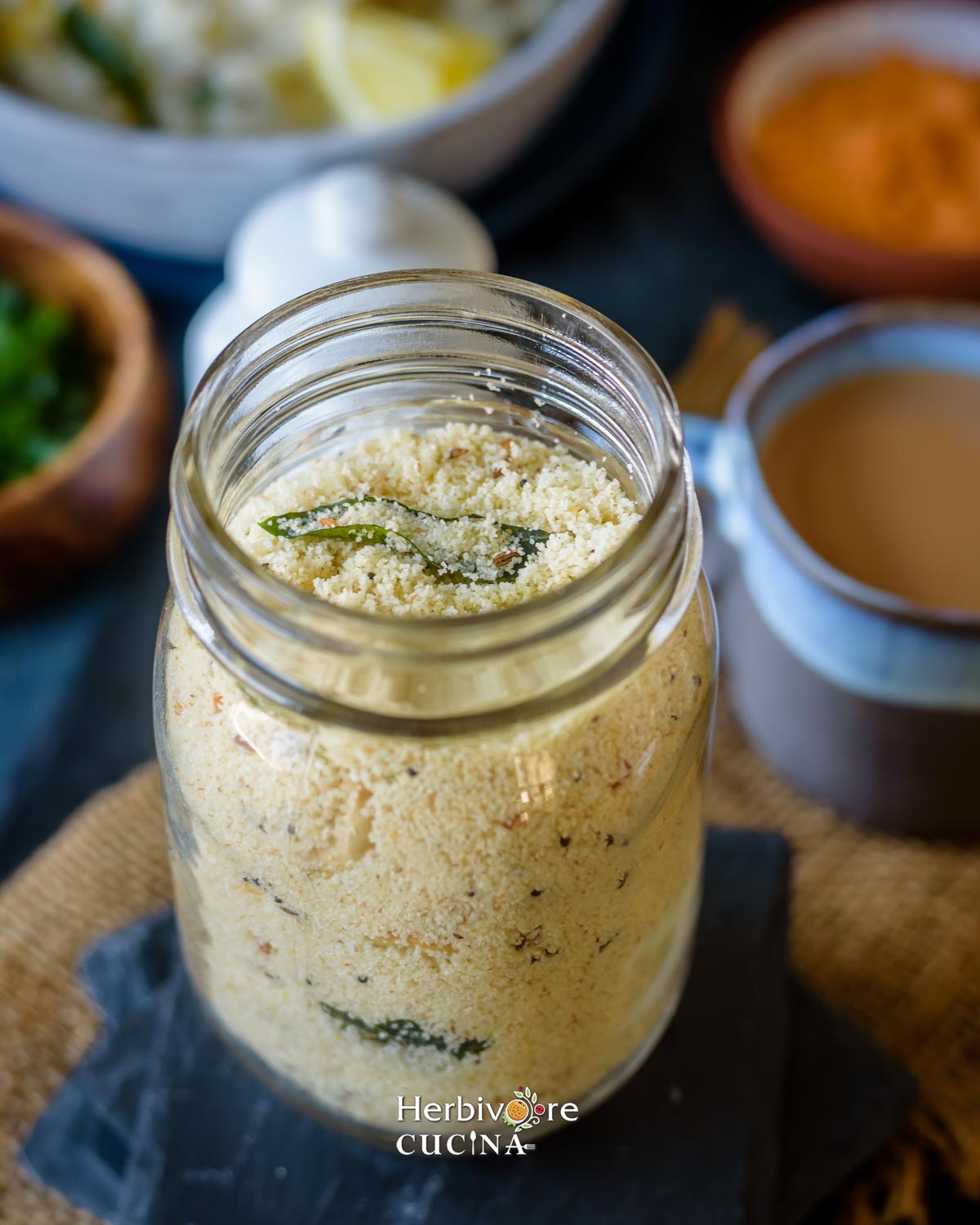 Side view of upma mix in a mason jar with a breakfast setup around it.