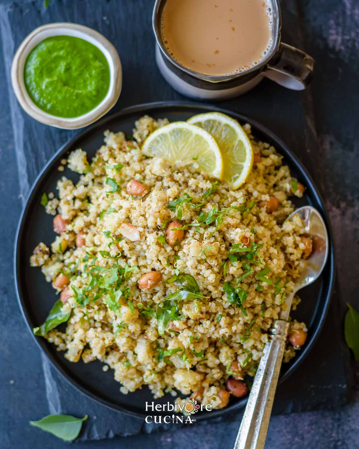 How to serve quinoa sabudana khichdi on a black plate with chutney and masala chai on a slate background.