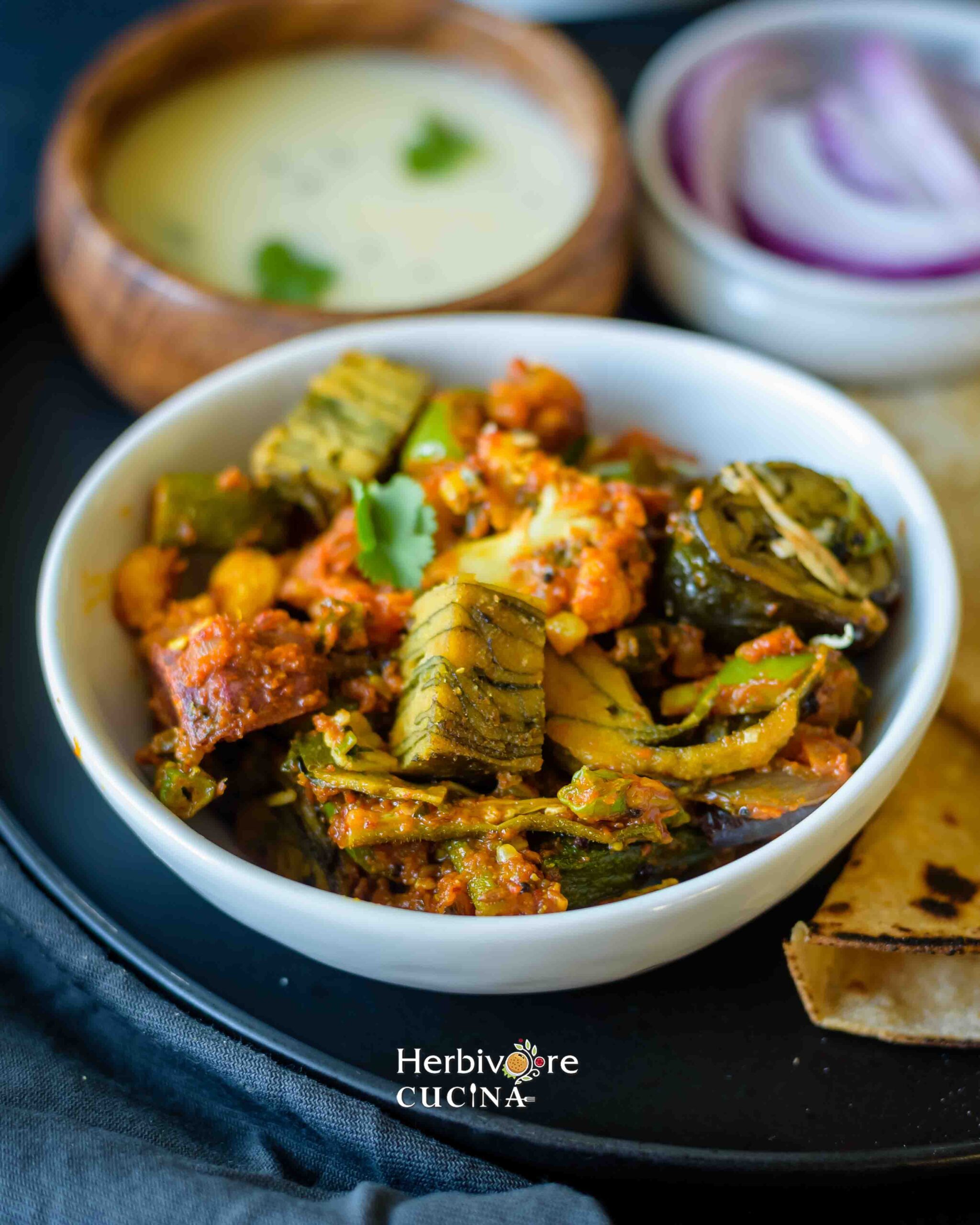 Indian style vegetable paatra sabji with Gujarati Kadhi, roti and onions in the background.