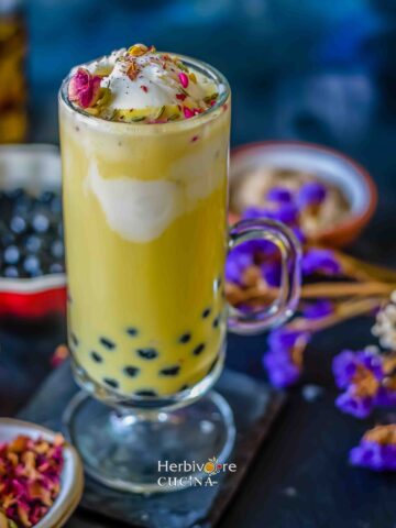 Boba thandai topped with ice-cream and all the toppings, against a backdrop with flowers and boba.