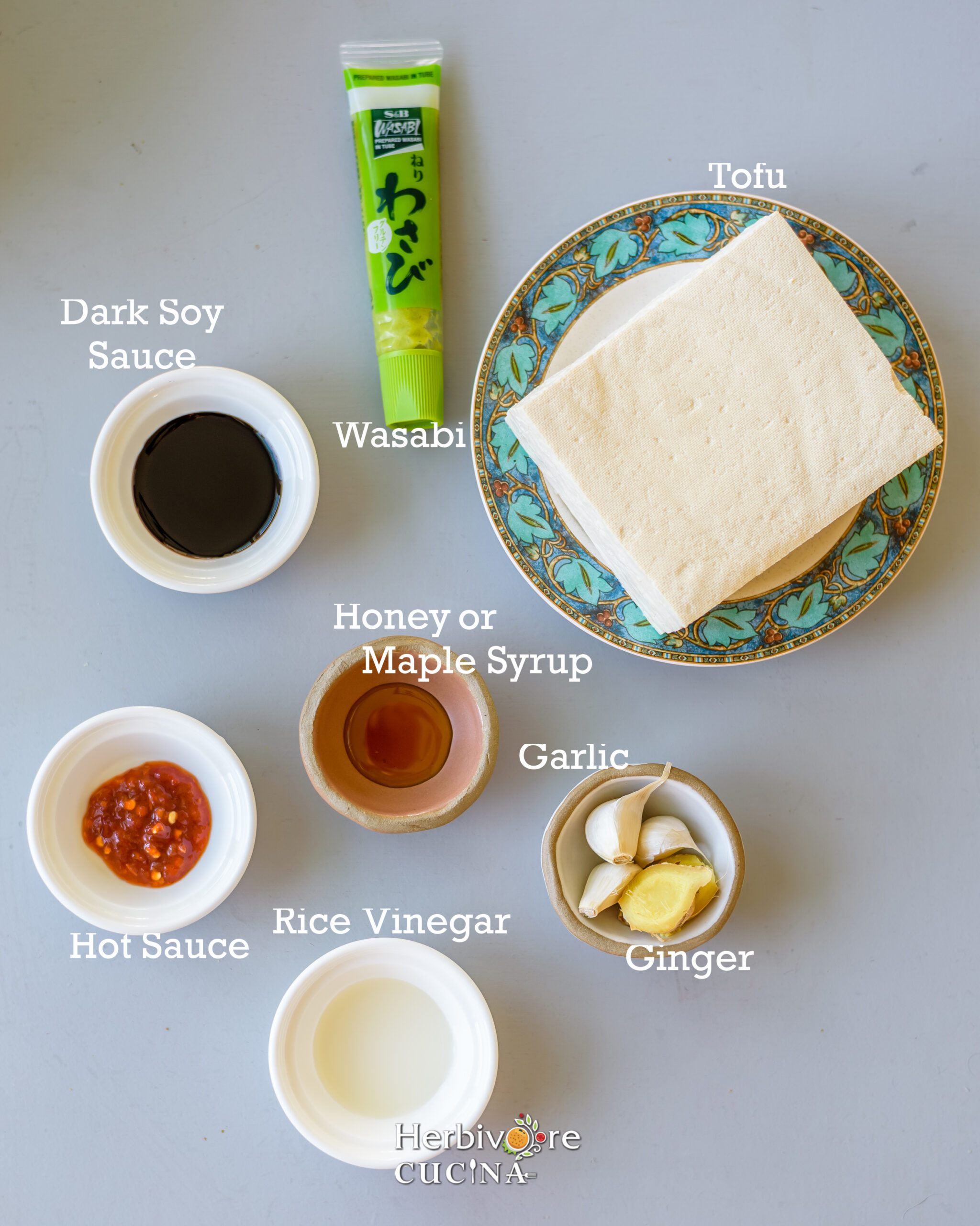 Ingredients for tofu poke; tofu, seasonings and sauces on gray background.