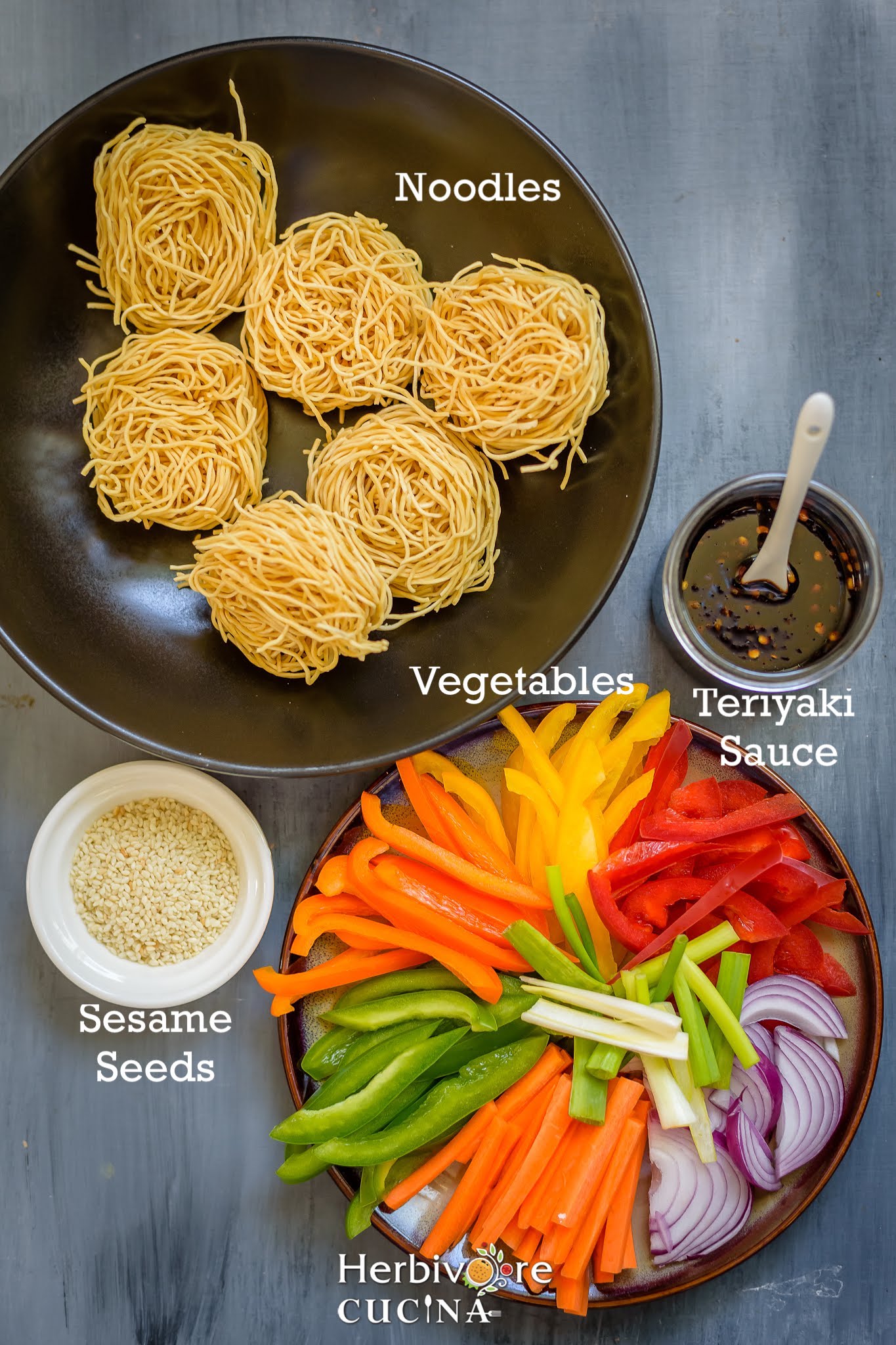 Ingredients for Vegetarian Teriyaki Noodles; noodles, vegetables and homemade teriyaki sauce on a gray board.