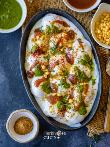 Instant Dahi Vada; fritters made with lentil and dunked in yogurt and toppings; served in black oval platter with toppings on the side.