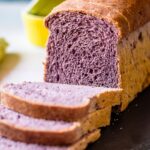 Purple sweet potato bread loaf placed on a slate plate with bowls on the side.