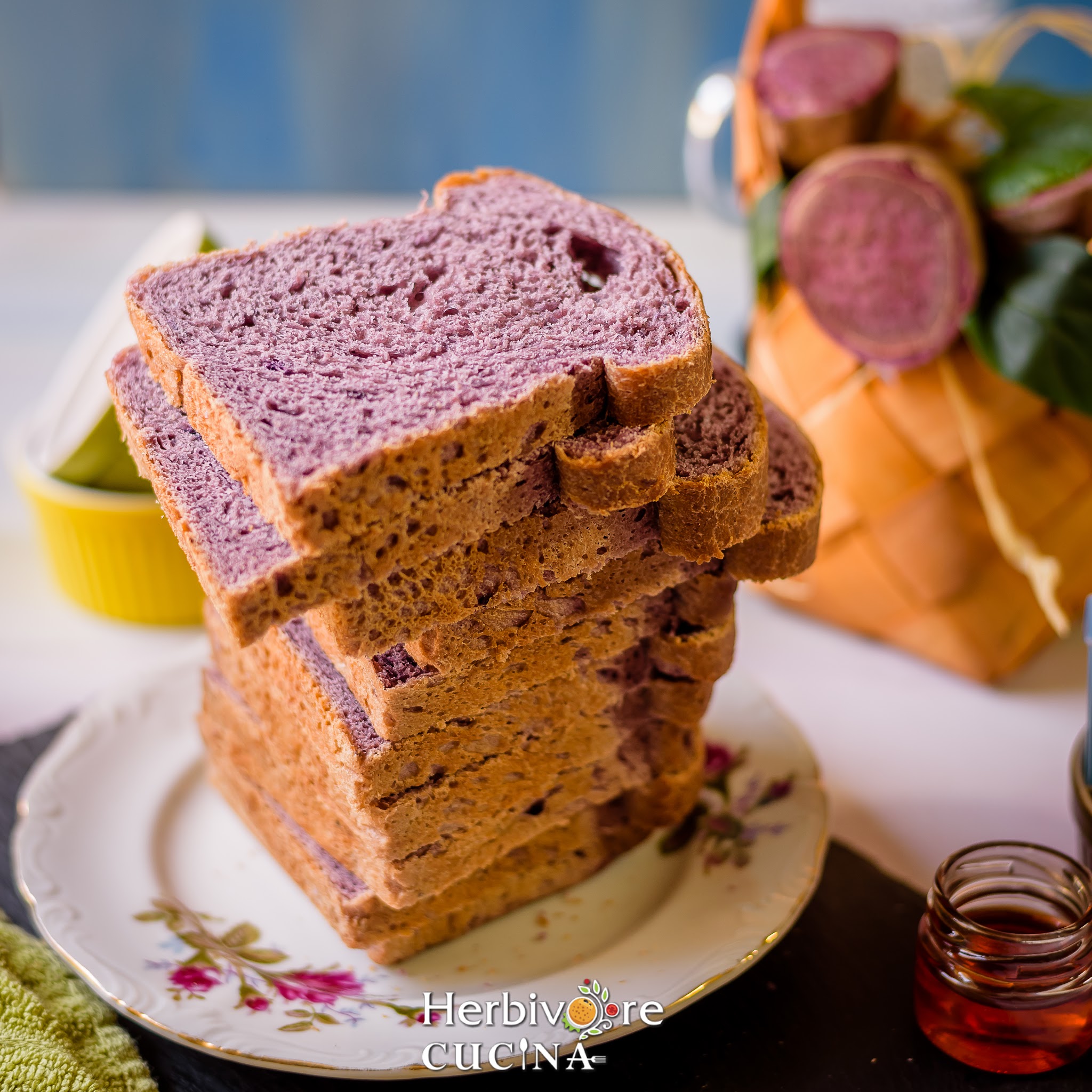 A stack of purple potato bread slices stacked on a white plate with some jelly on the side. 