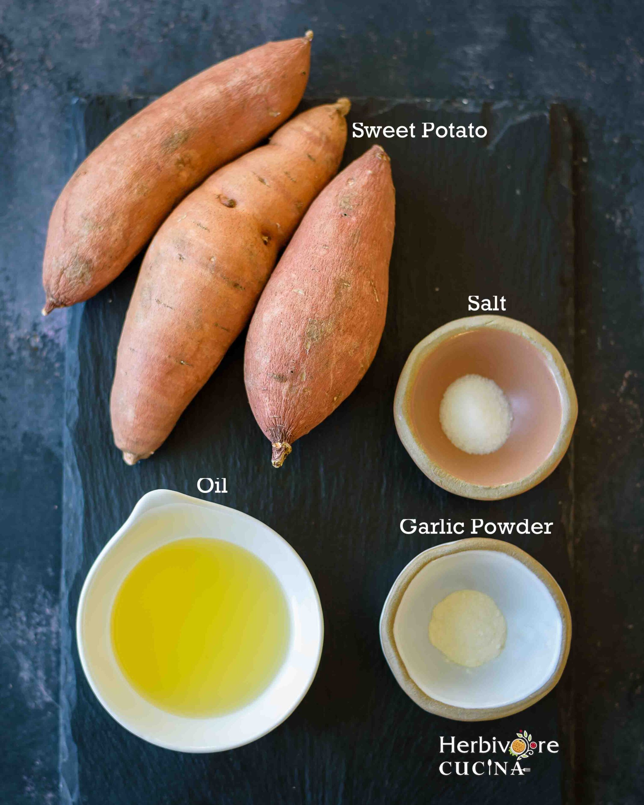 Ingredients for Air Fryer Sweet Potato Fries; sweet potato, oil, salt and garlic powder on a slate platter. 