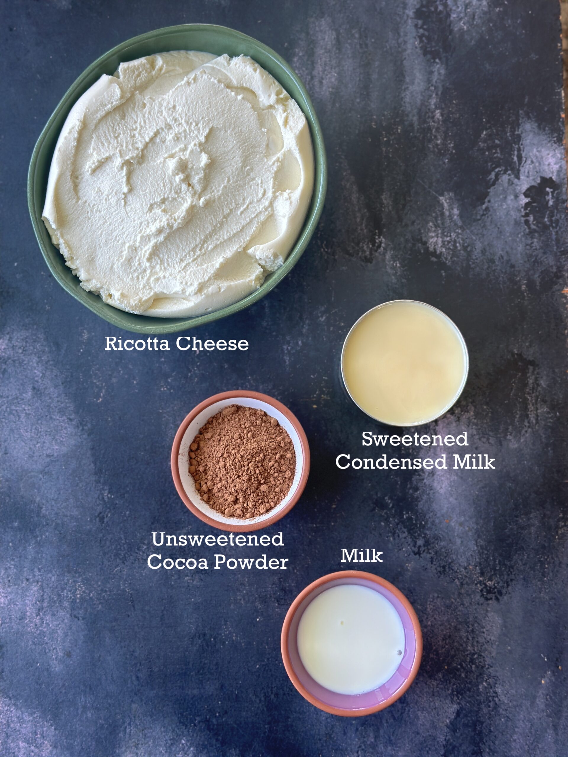 Ingredients of Ricotta Cheese Chocolate Peda on a black board. 