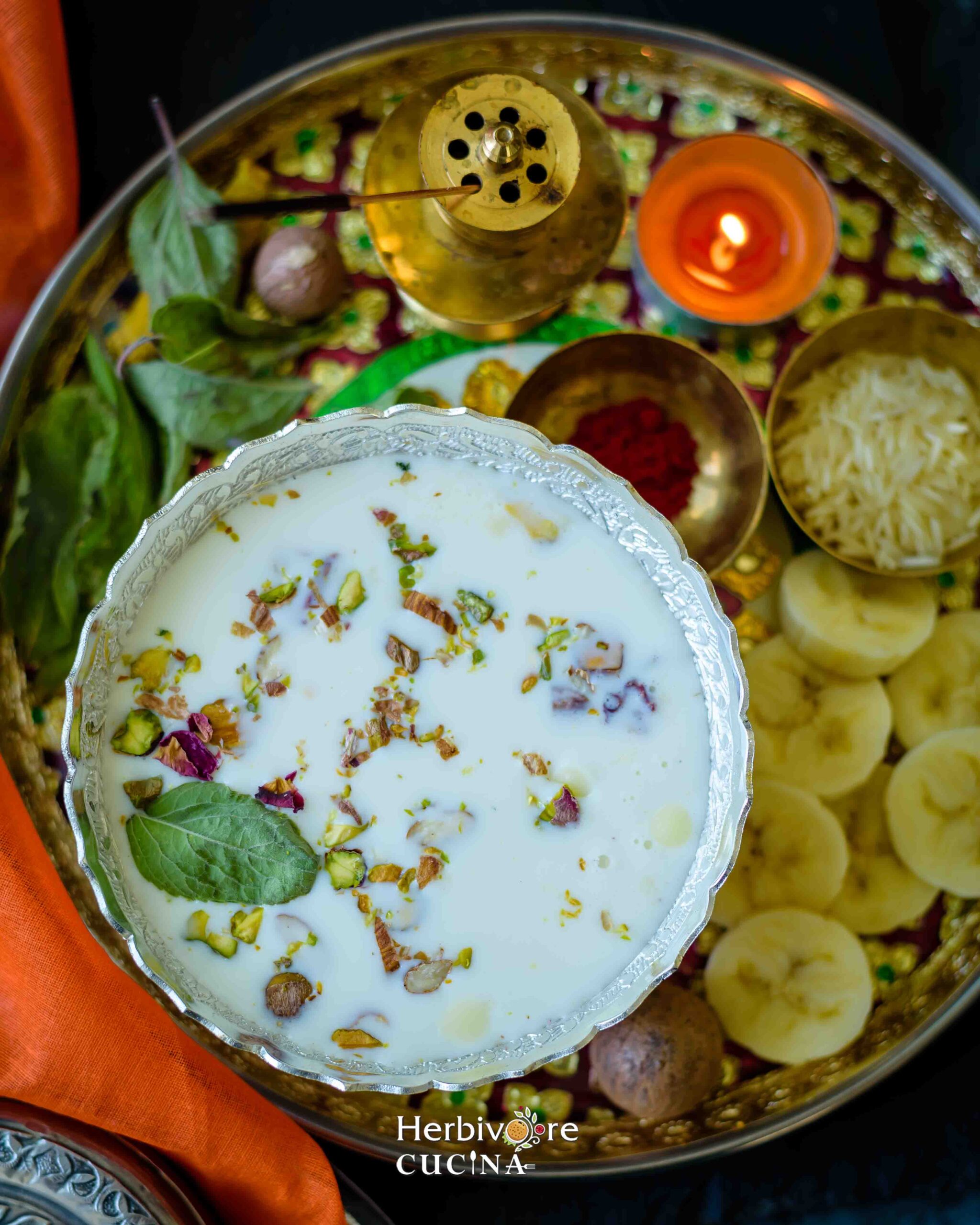 Top view of Panchamrit in a silver bowl with other pooja elements in the background in a plate.