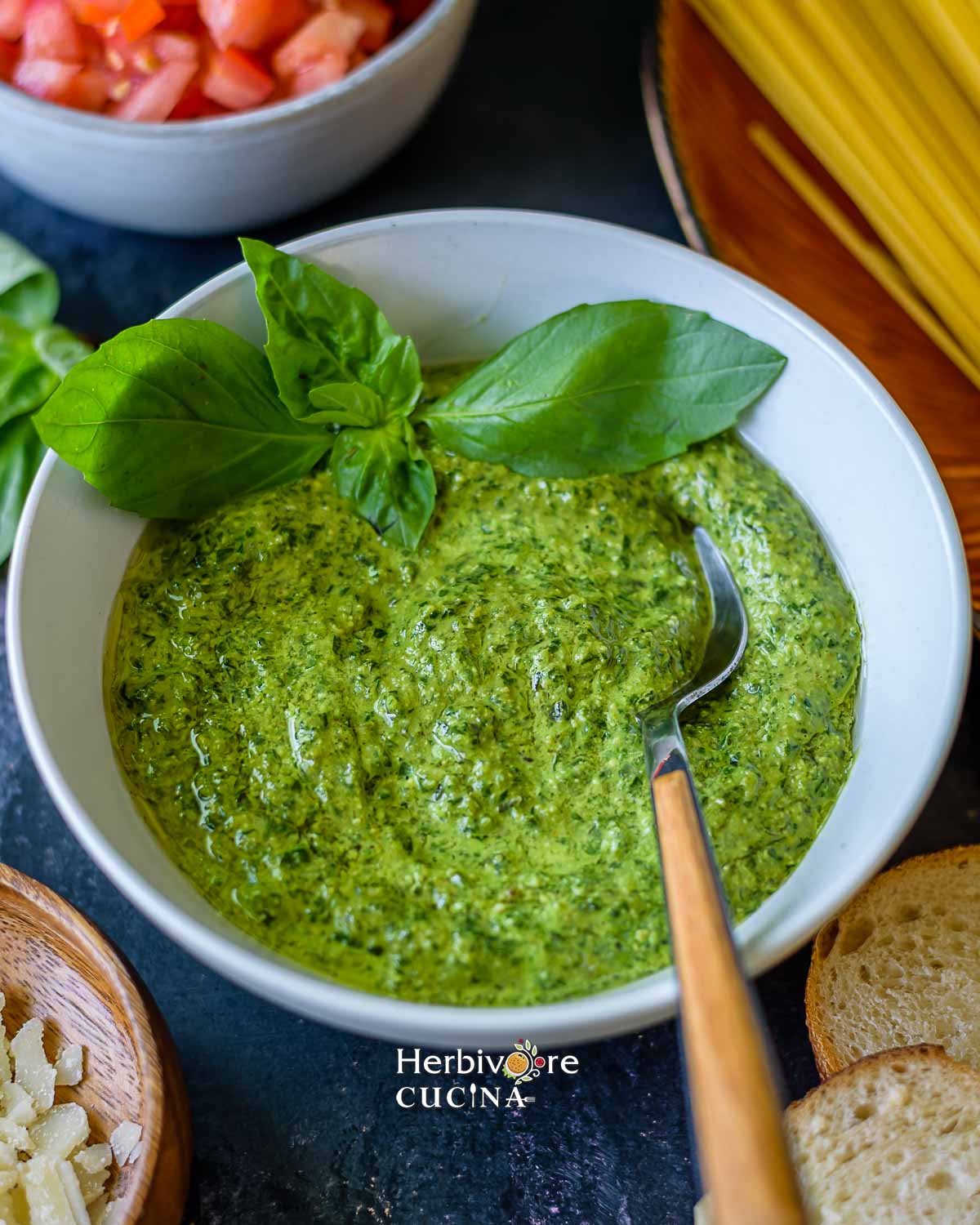 Basil pesto in a bowl with a spoon on the side. 