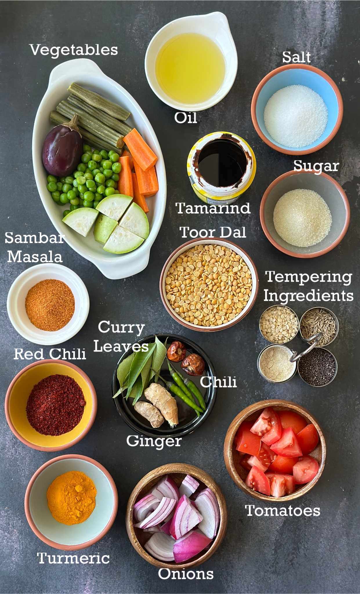 Ingredients to make sambar arranged in bowls on a board. 