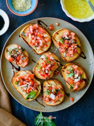 A brown plate with classic bruschetta topped with tomatoes and balsamic glaze.