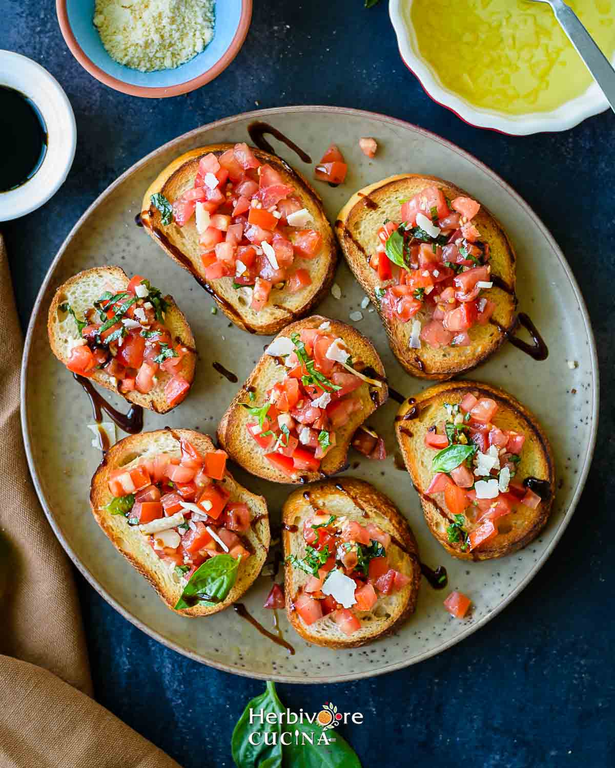 A brown plate with classic bruschetta topped with tomatoes and balsamic glaze. 