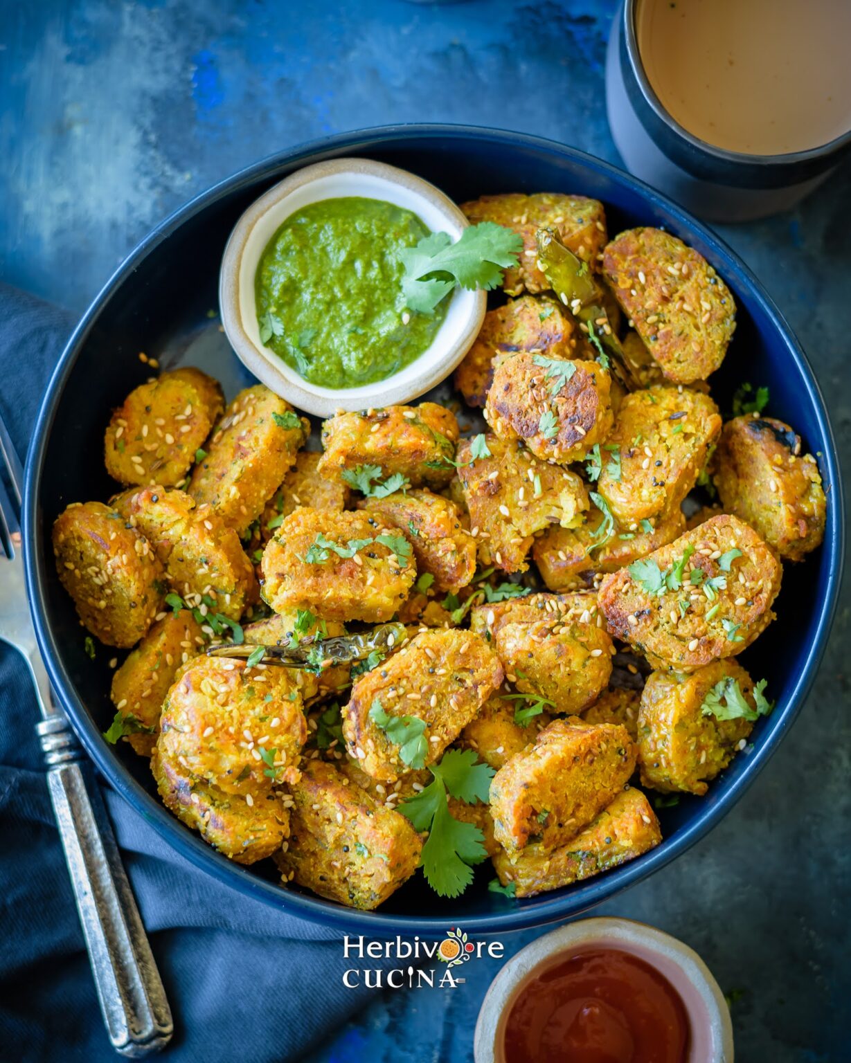 A plate filled with dudhi muthiya and a small bowl filled with cilantro chutney. 